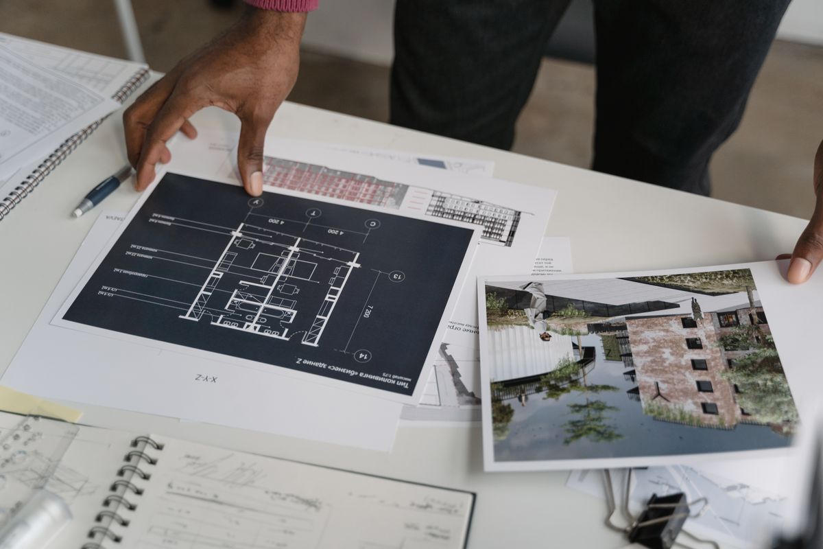 Revisão de plantas e documentos de uma edificação sobre a mesa
