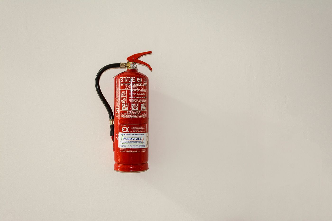 Extintor vermelho com mangueira e manômetro instalado na parede